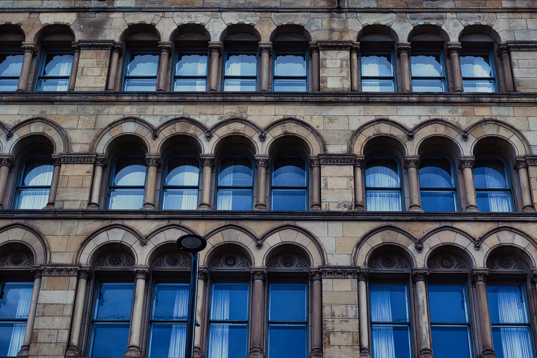 Stone Building Facade with Arched Windows in Manchester, UK.